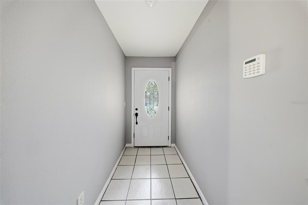 A narrow entryway features light gray walls, white tile flooring, and a white front door — 6308 N 22ND STREET, TAMPA, FL