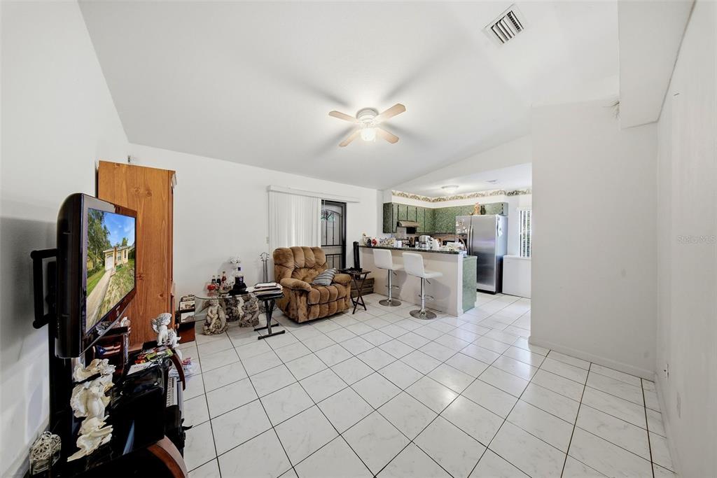 A living room with white tile floors flows into an open kitchen with a breakfast bar — 6308 N 22ND STREET, TAMPA, FL