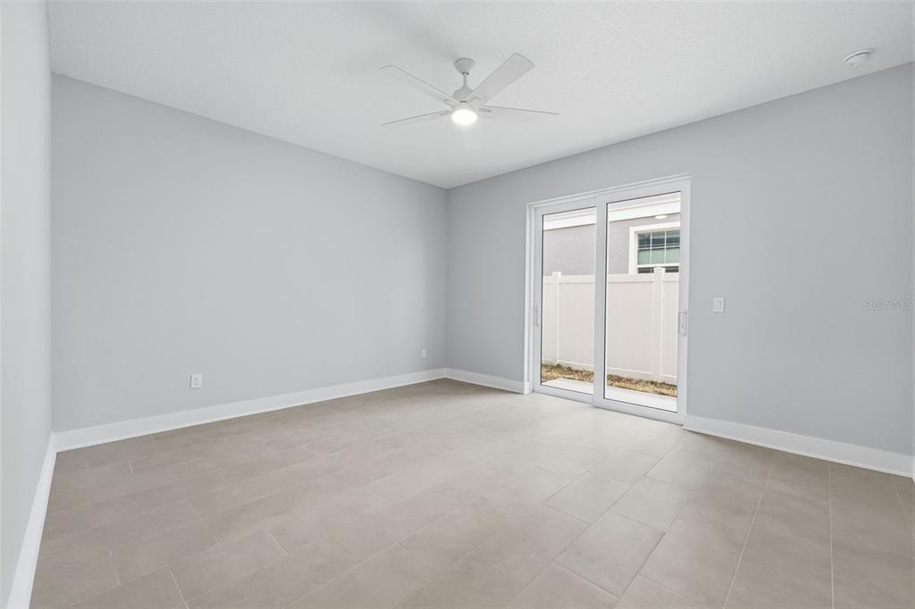 An empty room with light gray walls, tile flooring, a ceiling fan, and sliding glass doors — 4208 W CARMEN STREET UNIT C, TAMPA, FL