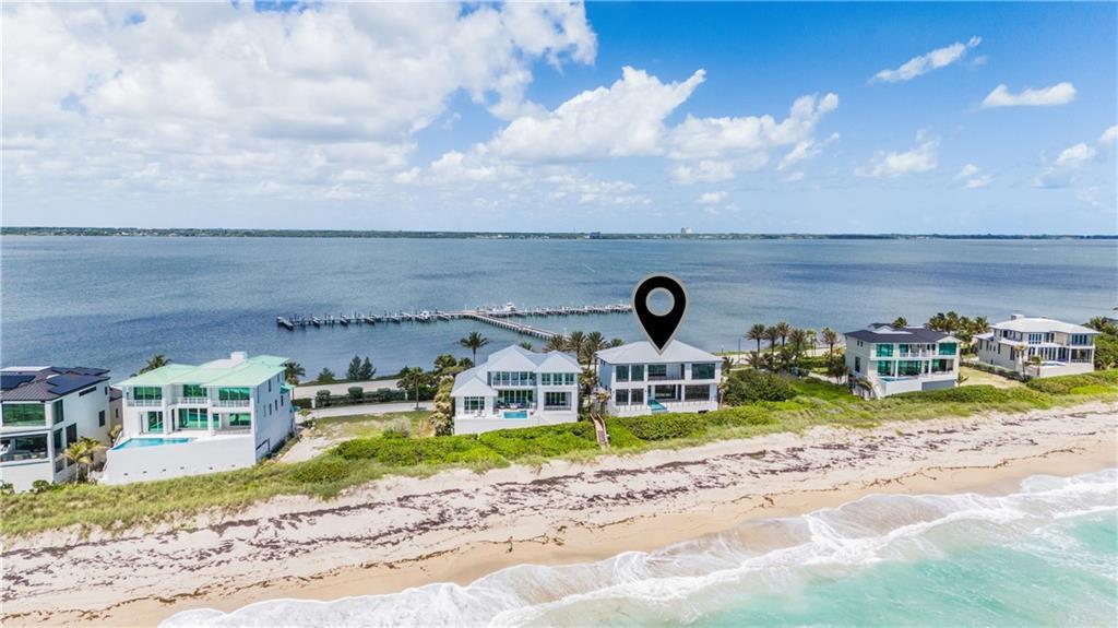An aerial view shows a row of beachfront houses along the coast with a pier — JENSEN BEACH, FL