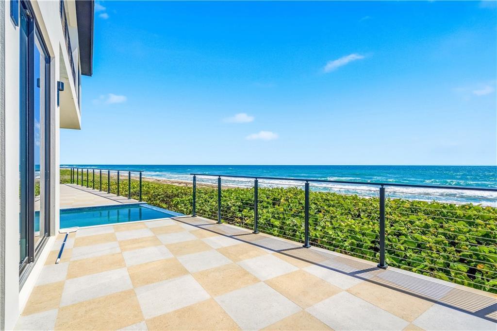 A tiled patio features a small pool and a metal railing overlooking the ocean — JENSEN BEACH, FL
