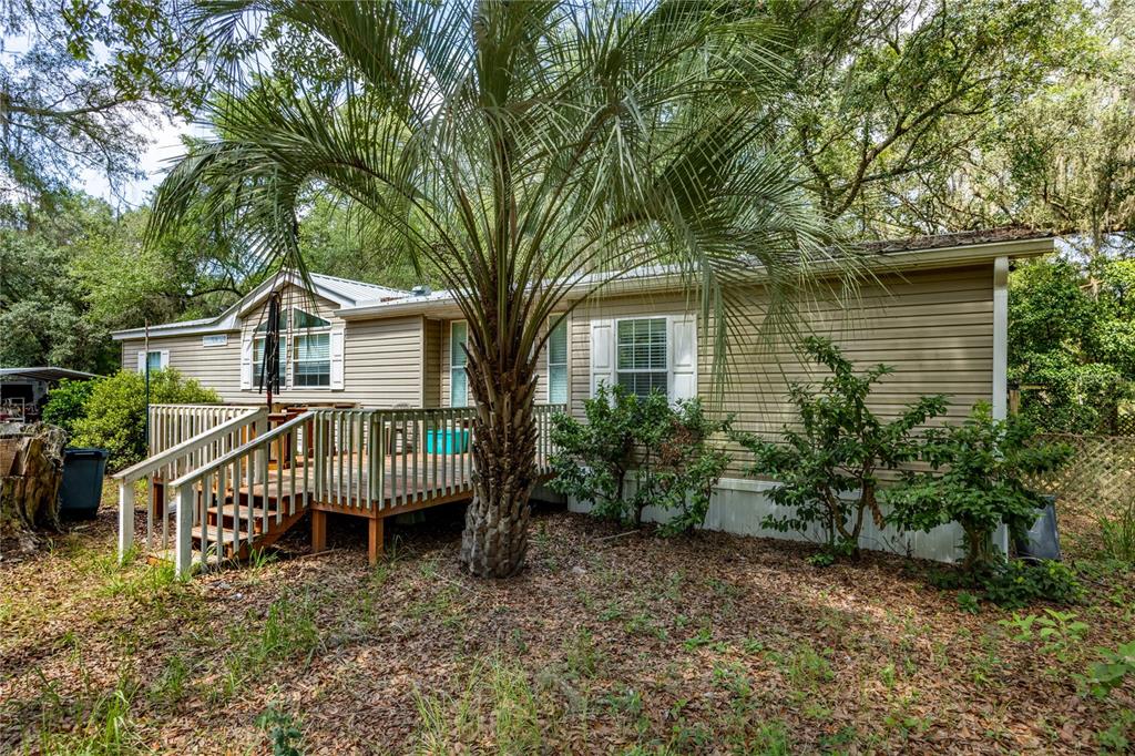 A tan mobile home features a wooden deck and a large palm tree in front — 819 LENORE AVENUE, INTERLACHEN, FL