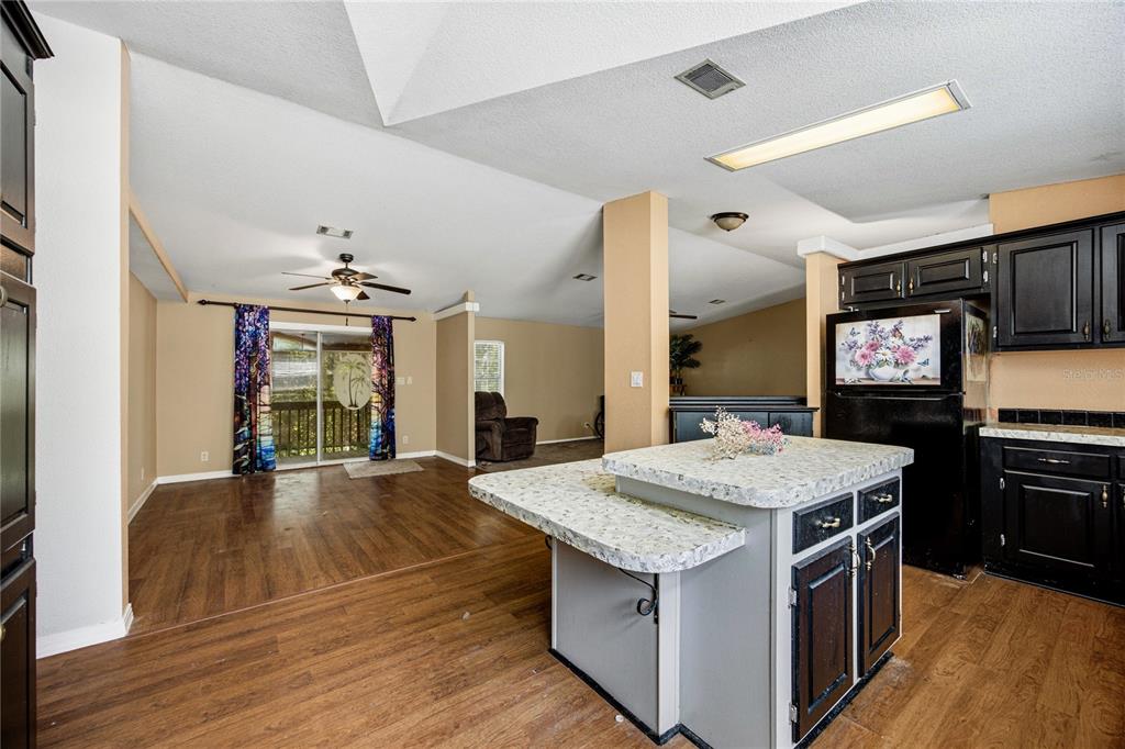 A kitchen with black cabinets and a tiered island overlooks an open-concept living area — 819 LENORE AVENUE, INTERLACHEN, FL