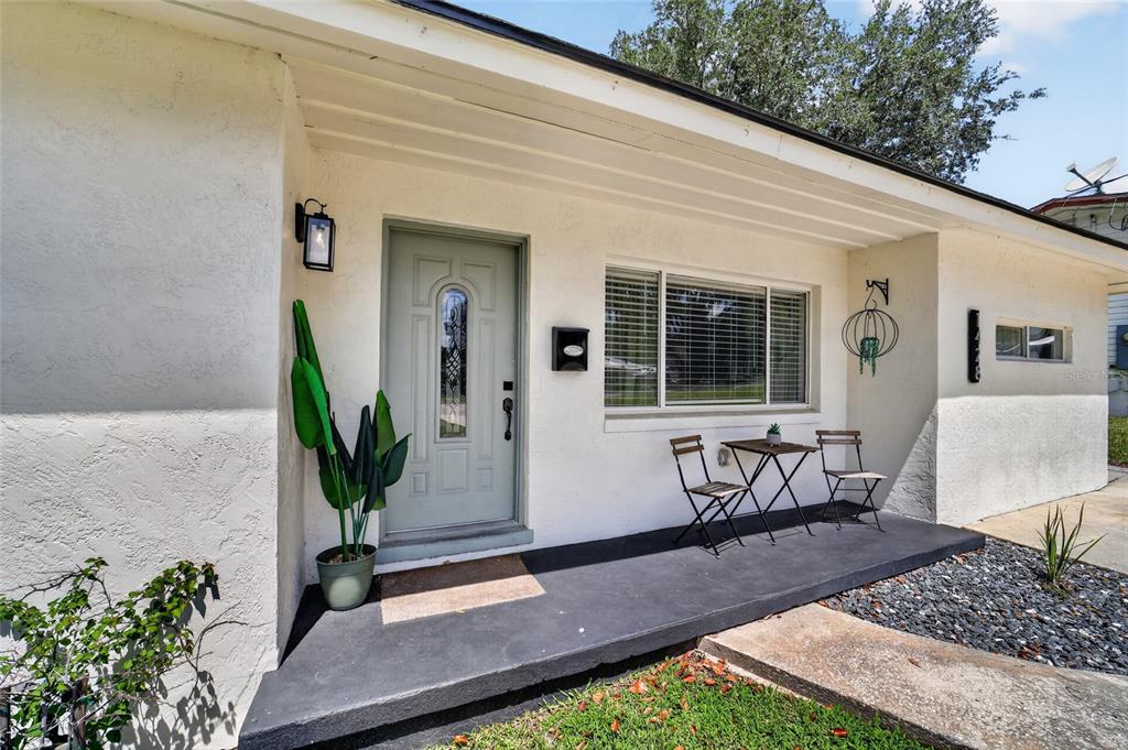 The exterior of a house features a light-colored facade, a sage green door, and a porch — 1428 SE 9TH AVENUE, OCALA, FL