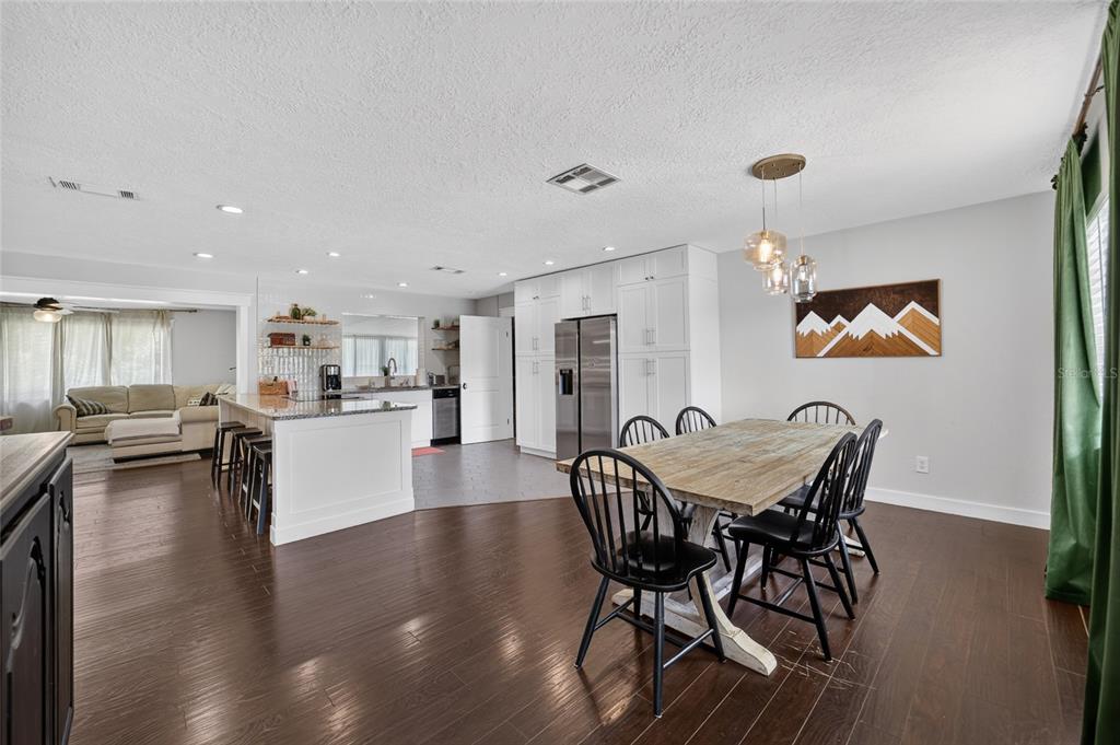 A dining area with a wooden table and black chairs sits beside a modern kitchen — 1428 SE 9TH AVENUE, OCALA, FL