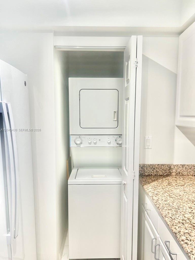 A stacked washer and dryer unit is located in a closet next to a kitchen — 1155 BRICKELL BAY DR # 807, Miami FL 33131, MIAMI, FL