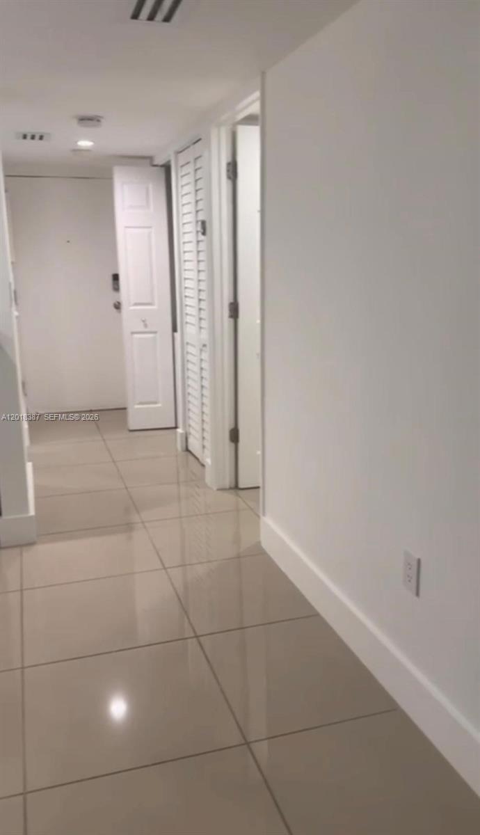A hallway with light-colored tile flooring leads toward an open doorway and a white door — 8004 SW 149th Ave # C418, Miami FL 33193, MIAMI, FL