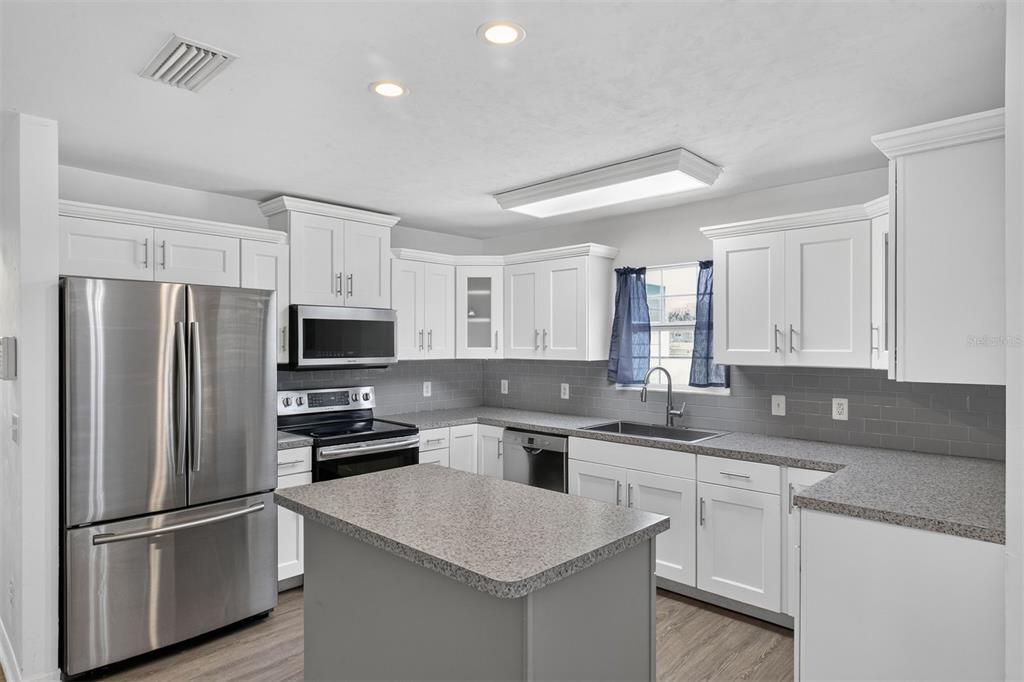 A kitchen with white cabinets, gray countertops, stainless steel appliances, and a central island — 9892 SW 95TH PLACE, GAINESVILLE, FL