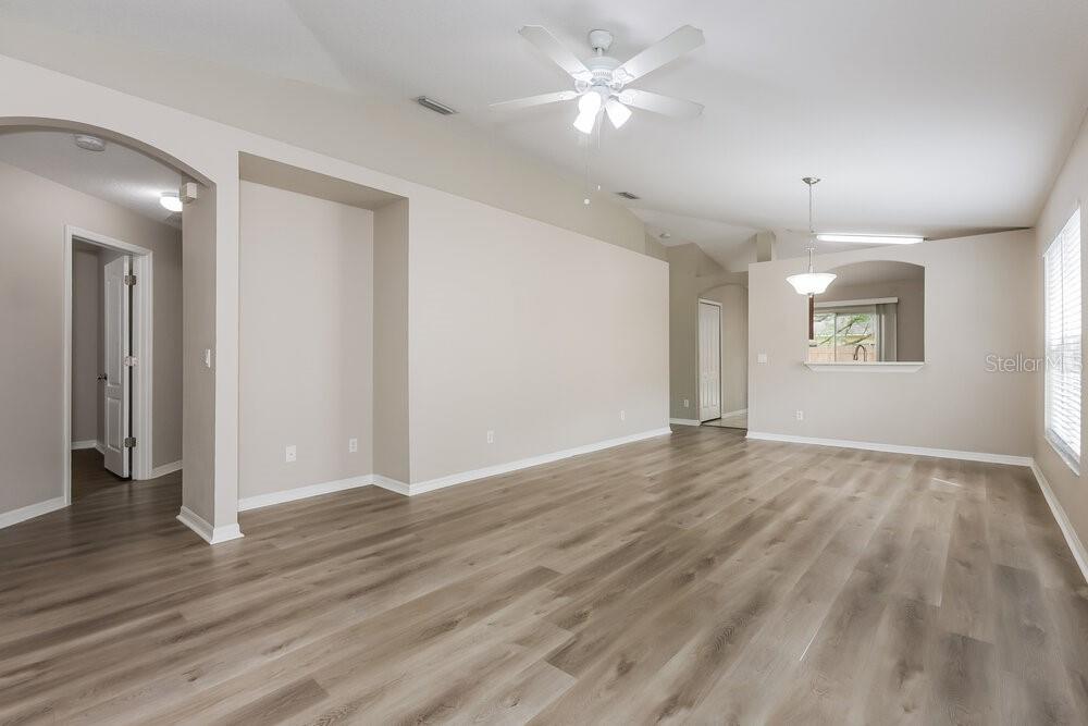 A spacious living room features light-colored walls, wood-look flooring, and a ceiling fan — 1038 HARVEST MOON DRIVE, SEFFNER, FL