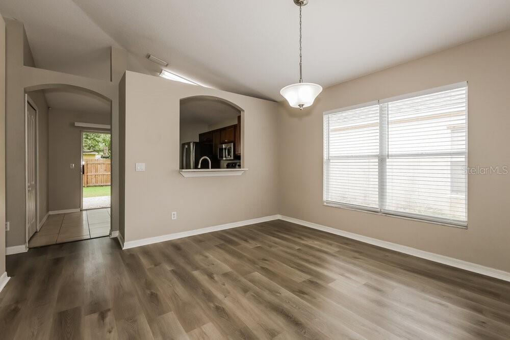 A dining area features wood-look flooring, beige walls, a pendant light, and a kitchen pass-through — 1038 HARVEST MOON DRIVE, SEFFNER, FL