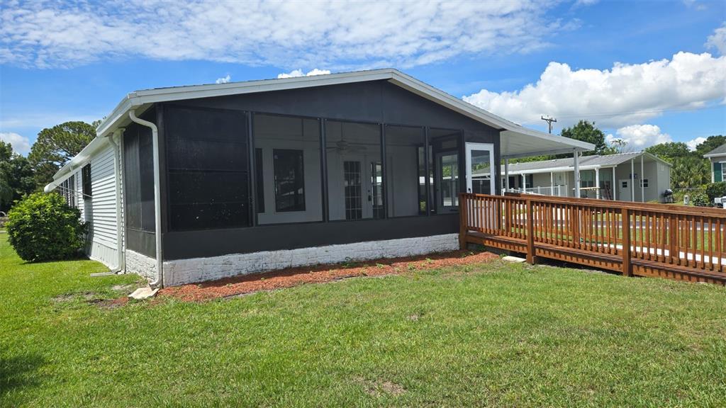 A mobile home with a screened-in porch and a wooden wheelchair ramp on the side — 3905 SUGAR BERRY PLACE, COCOA, FL