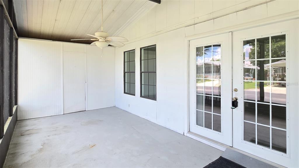 A covered porch with white walls, a ceiling fan, two windows, and a glass-paned door — 3905 SUGAR BERRY PLACE, COCOA, FL