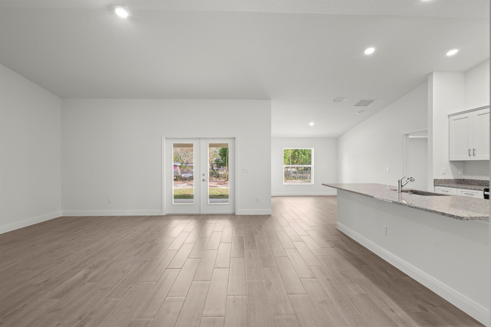 An open-concept living area features light wood-look tile flooring, white walls, and a kitchen island — 16227 69th Street N, Loxahatchee FL 33470, LOXAHATCHEE, FL