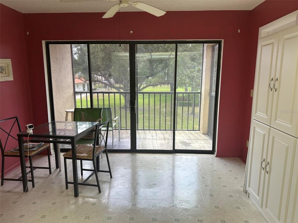 A dining area features a glass-top table, tile flooring, white cabinets, and sliding glass doors — 5090 BAY STREET NE UNIT 220, ST PETERSBURG, FL