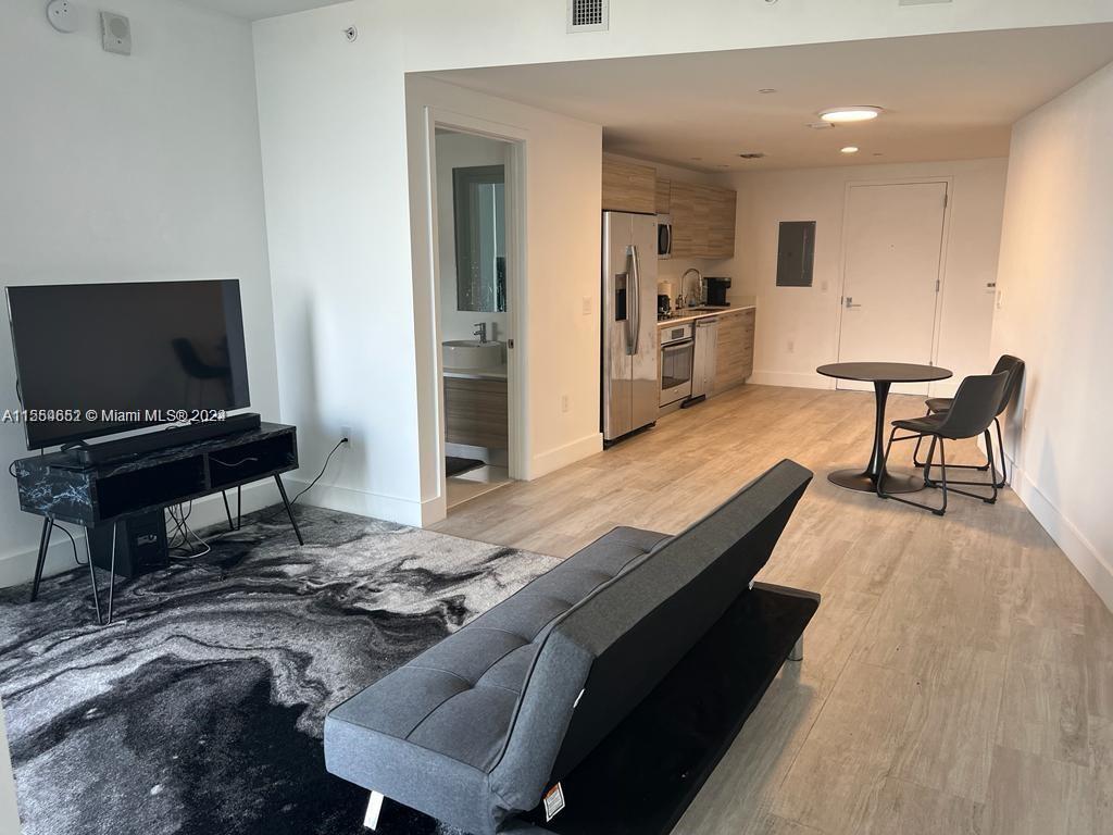 This studio apartment features a kitchen, living area with a sofa, and a dining table — 121 NE 34th St # 2014, Miami FL 33137, MIAMI, FL