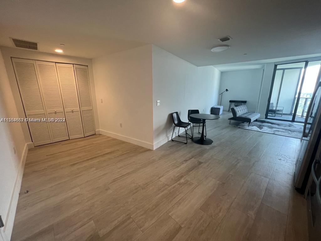 An open-concept living area features light wood-look flooring, a dining set, and a closet — 121 NE 34th St # 2014, Miami FL 33137, MIAMI, FL