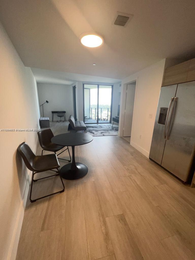 A modern apartment features a dining area with a round table and light wood flooring — 121 NE 34th St # 2014, Miami FL 33137, MIAMI, FL