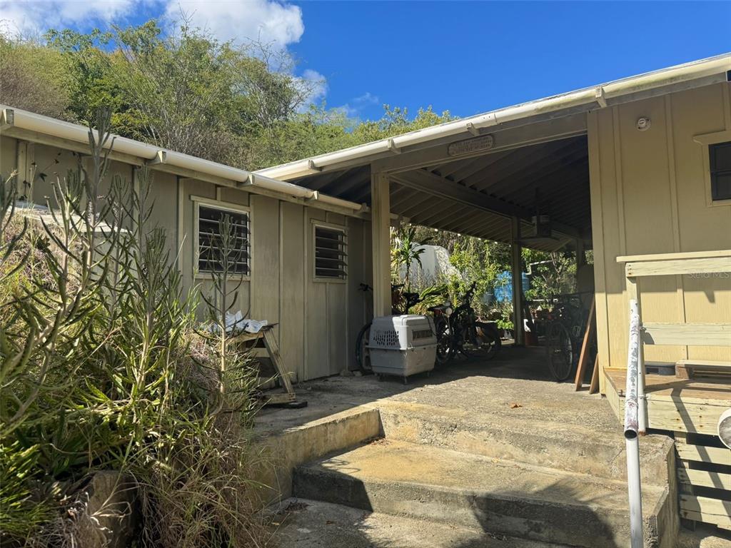 An exterior view of a house featuring a covered carport, concrete steps, and louvered windows — 4 BARRIO PLAYA SARDINAS, CULEBRA, PR
