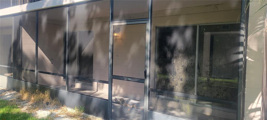 A screened-in porch with a metal door and sliding glass windows overlooking a grassy area — 180 MAGNOLIA WOODS COURT UNIT 9C, DELTONA, FL