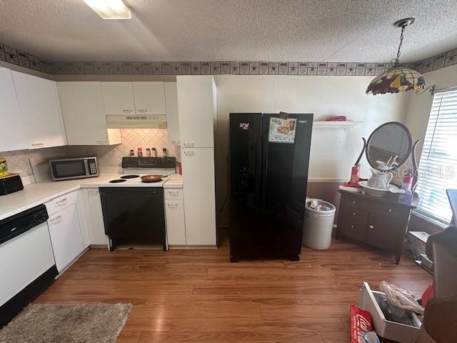 A kitchen features white cabinets, a black refrigerator, a black stove, and wood-look flooring — 5445 18TH COURT W, BRADENTON, FL