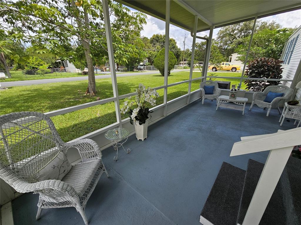 A screened-in porch with blue painted flooring, white wicker furniture, and a view of grass — 1340 SAWDUST TRAIL, KISSIMMEE, FL