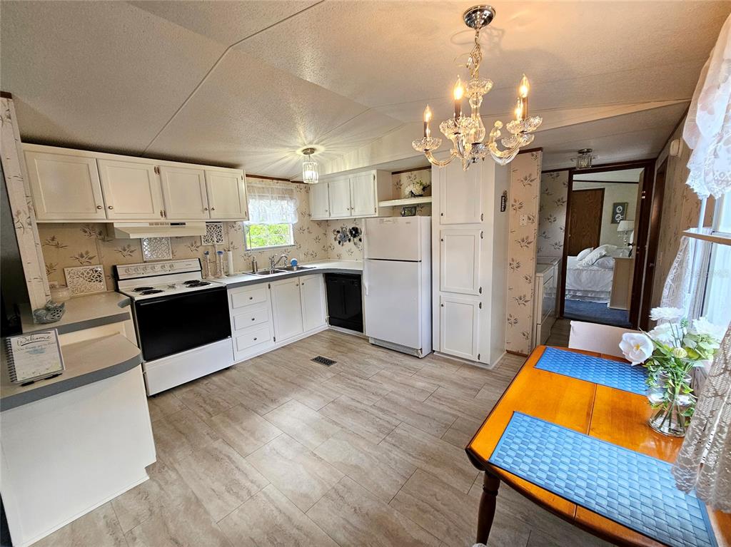 A kitchen with white cabinets, a black stove, and a dining table with blue placemats — 1340 SAWDUST TRAIL, KISSIMMEE, FL