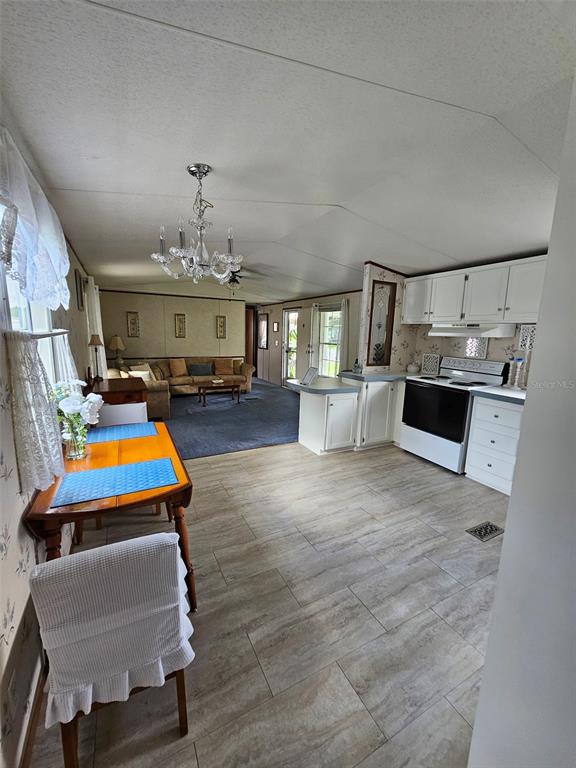 An open-concept kitchen and dining area features white cabinets, tile flooring, and a crystal chandelier — 1340 SAWDUST TRAIL, KISSIMMEE, FL
