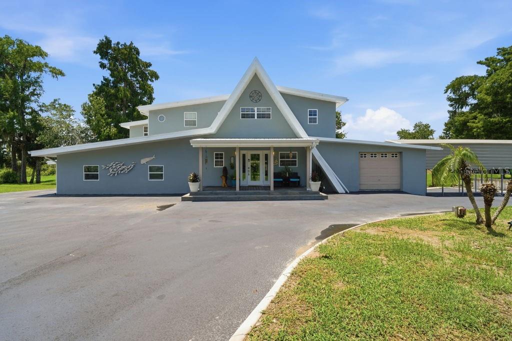 A two-story, light blue house with a prominent A-frame roof and an attached garage — 220 BRANDY COURT, DELTONA, FL