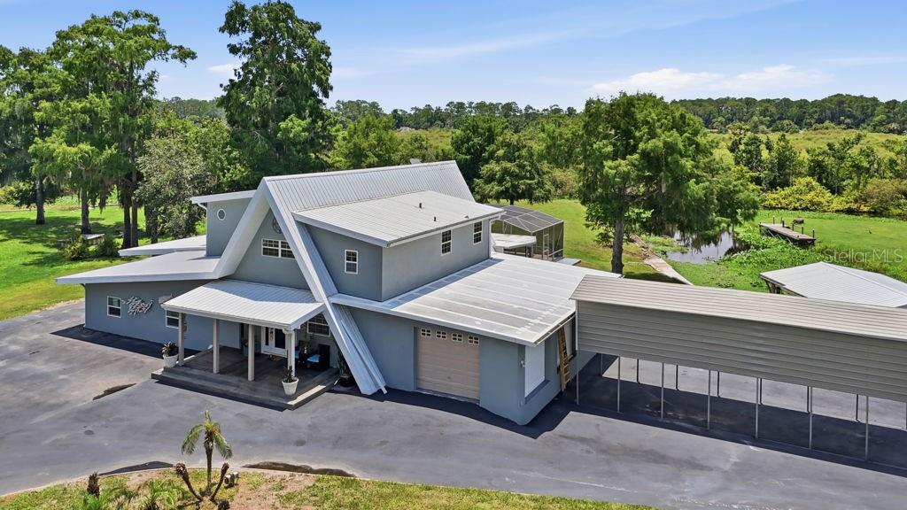 An aerial view of a gray house with a metal roof and a long carport — 220 BRANDY COURT, DELTONA, FL