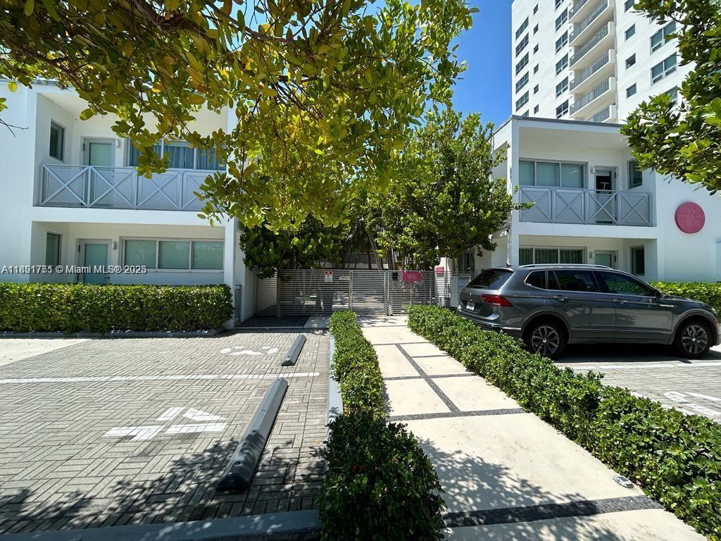 A gray SUV is parked in front of two-story white buildings with balconies and landscaping — 1816 Meridian Ave # 18, Miami Beach FL 33139, MIAMI BEACH, FL