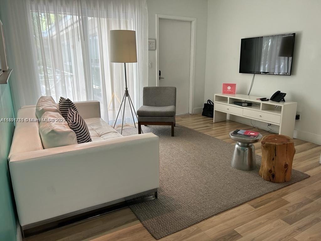 A living room features a white sofa, a grey armchair, and a television on a stand — 1816 Meridian Ave # 18, Miami Beach FL 33139, MIAMI BEACH, FL