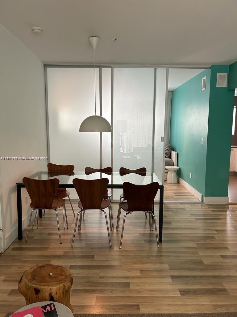 A dining area features a glass table, wooden chairs, and a sliding glass room divider — 1816 Meridian Ave # 18, Miami Beach FL 33139, MIAMI BEACH, FL
