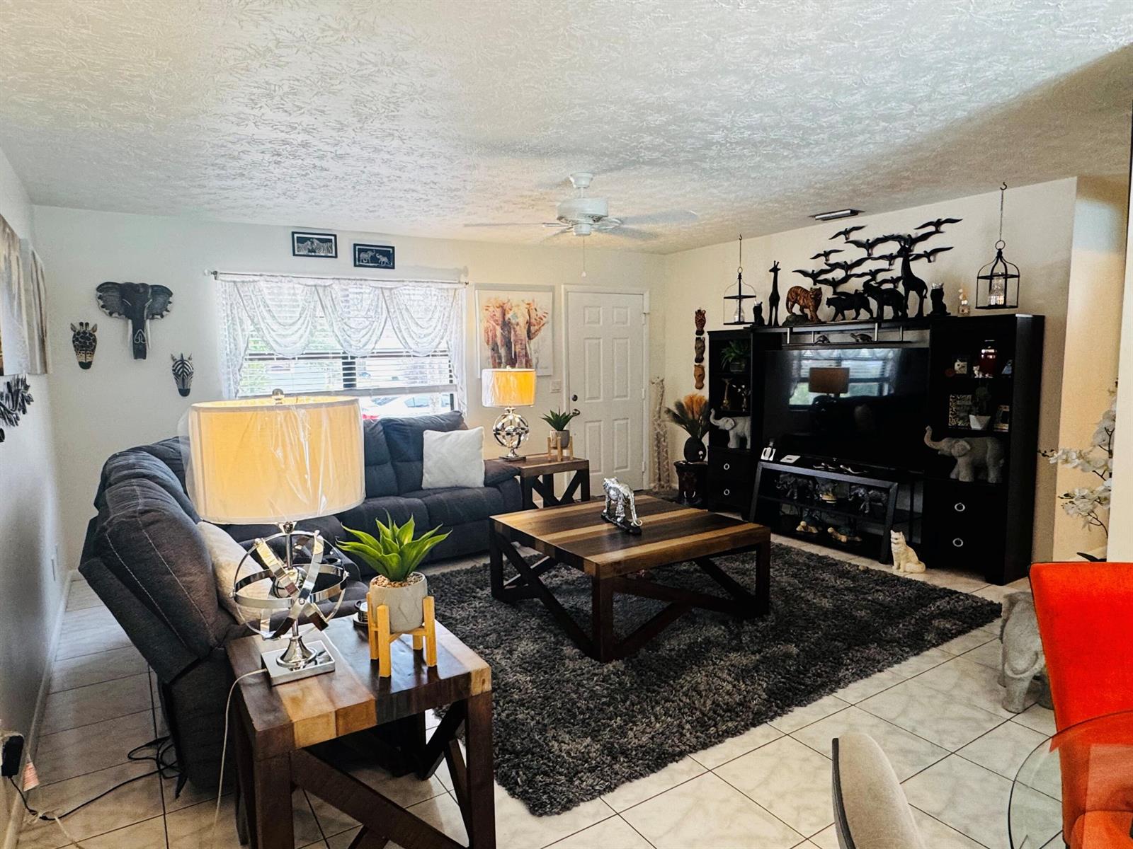 A living room features a dark sectional sofa, a wooden coffee table, and animal-themed decor — 1918 SE Monroe Street, Stuart FL 34997, STUART, FL