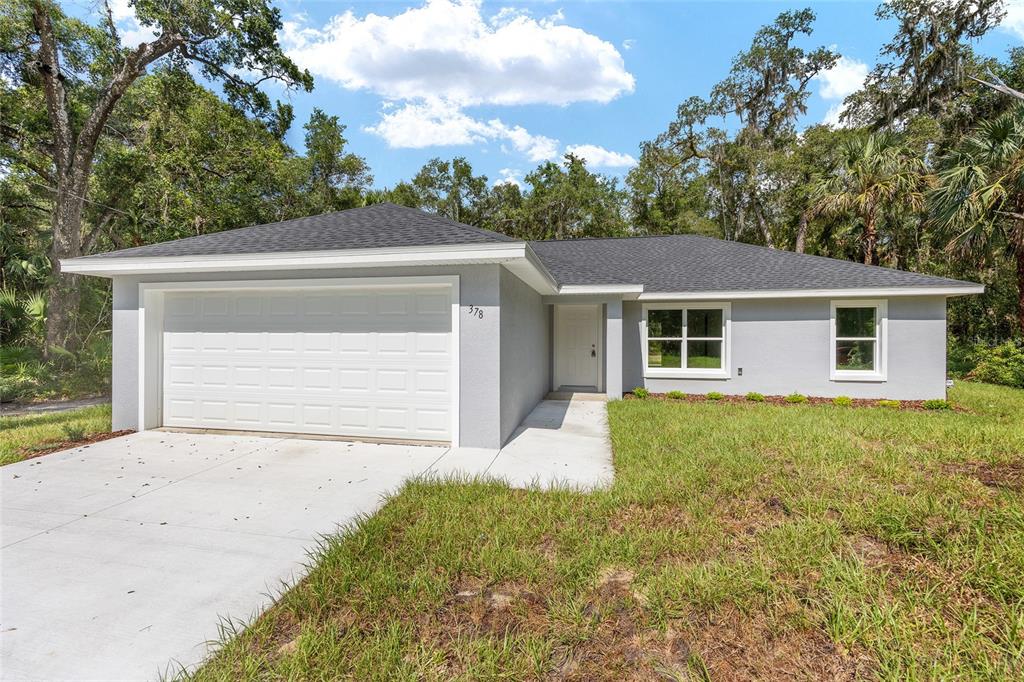 A single-story gray house with a white garage door and a concrete driveway — 202 FISHER LOOP, OCKLAWAHA, FL