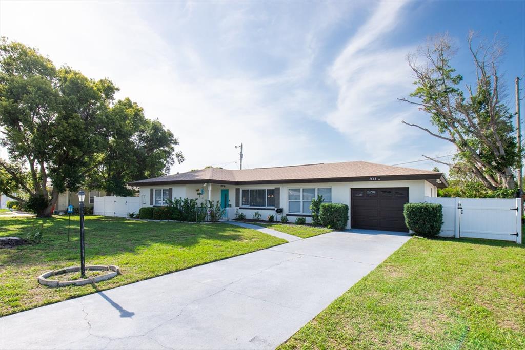 A single-story house with a white exterior, brown roof, and a bright blue front door — 1468 LEMON STREET, CLEARWATER, FL