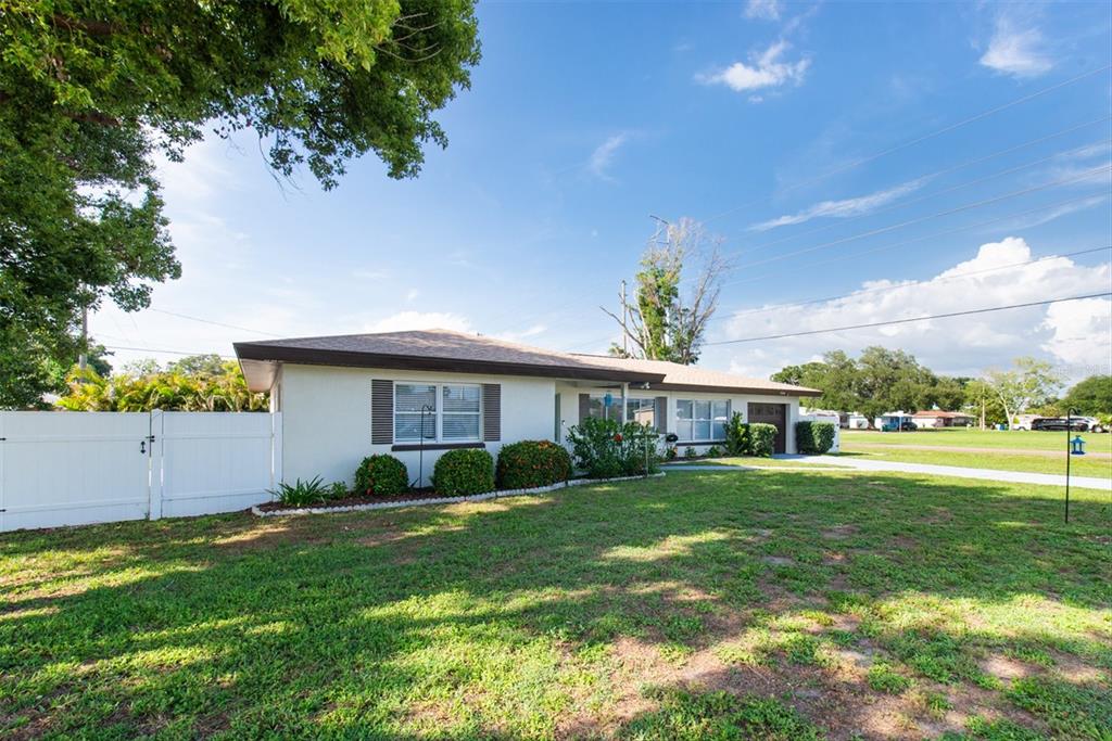 A single-story house with a white exterior, brown roof, and a white vinyl fence — 1468 LEMON STREET, CLEARWATER, FL
