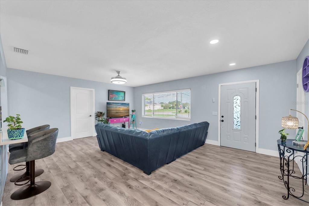A living room features a blue sectional sofa, light wood floors, and a front door — 1468 LEMON STREET, CLEARWATER, FL