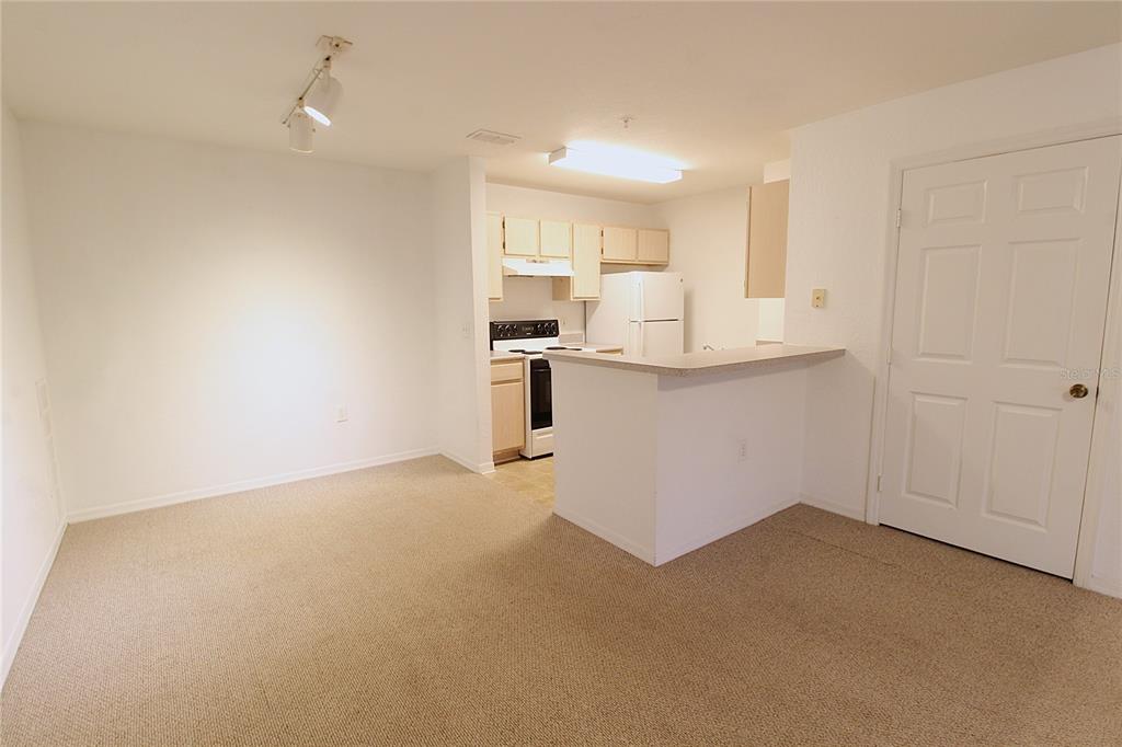 A carpeted dining area opens to a kitchen with white appliances and a breakfast bar — 8905 MANOR LOOP UNIT 107, BRADENTON, FL