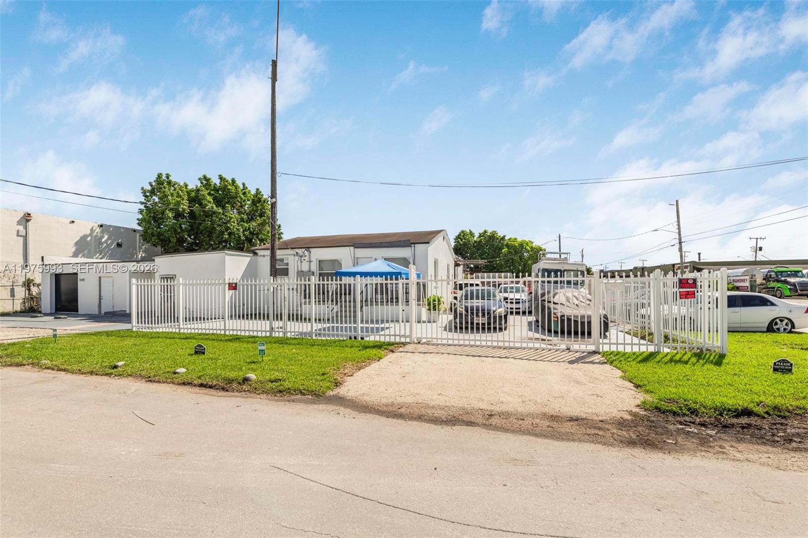 A fenced-in property features a small white building, a blue canopy, and several parked vehicles — 3705 NW 35th Ave, Miami FL 33142, MIAMI, FL