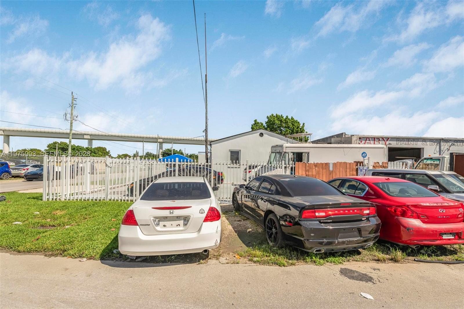 A white Honda, a black Dodge, and a red Infiniti are parked in front of a building — 3705 NW 35th Ave, Miami FL 33142, MIAMI, FL