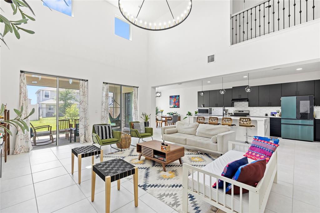 A spacious open-concept living room and kitchen with high ceilings and tile flooring — 7647 MODICA STREET, CLERMONT, FL