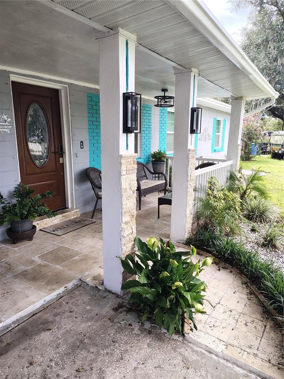 A covered front porch features stone-based columns, turquoise brick accents, and a wooden front door — 607 OAK RIDGE DRIVE, BRANDON, FL