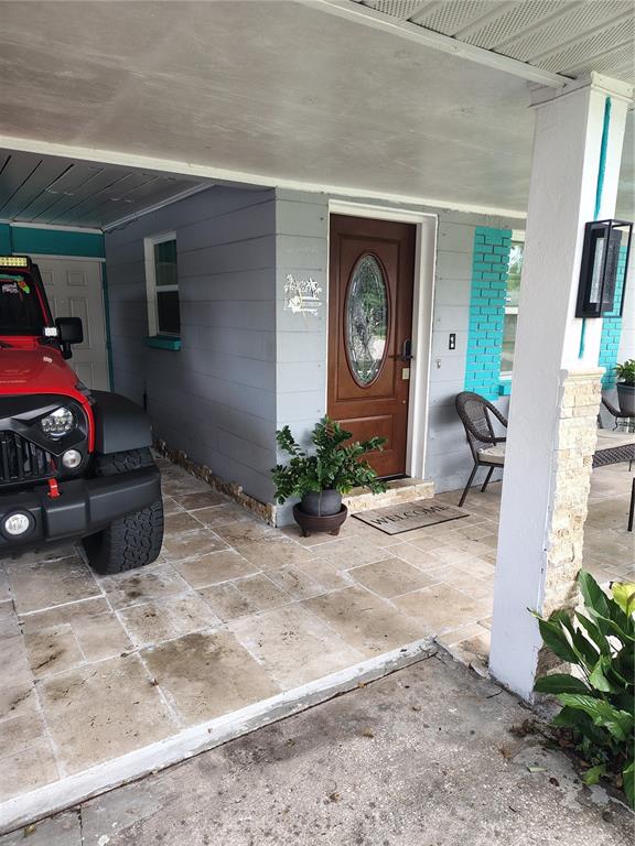 A covered porch features stone tile flooring, a brown front door, and a parked Jeep — 607 OAK RIDGE DRIVE, BRANDON, FL