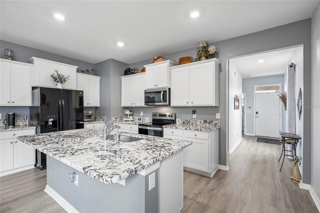 A kitchen features white cabinets, granite countertops, a central island, and stainless steel appliances — 5395 SUNSHINE DRIVE, WILDWOOD, FL
