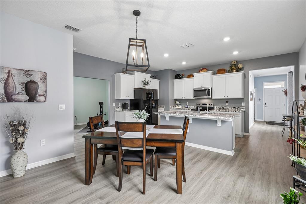 A dining area with a wooden table and chairs sits before an open-concept kitchen — 5395 SUNSHINE DRIVE, WILDWOOD, FL