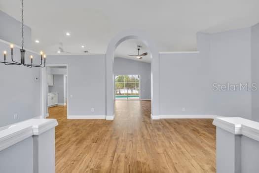 An open-concept living area features light gray walls, wood-look flooring, and an arched entryway — 1913 MAGIES COURT, OVIEDO, FL