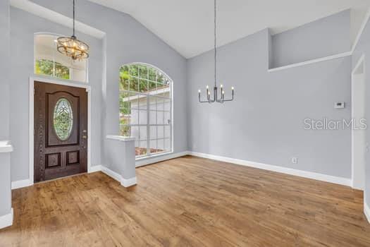 An entryway with wood flooring, a dark wood front door, and a modern chandelier — 1913 MAGIES COURT, OVIEDO, FL