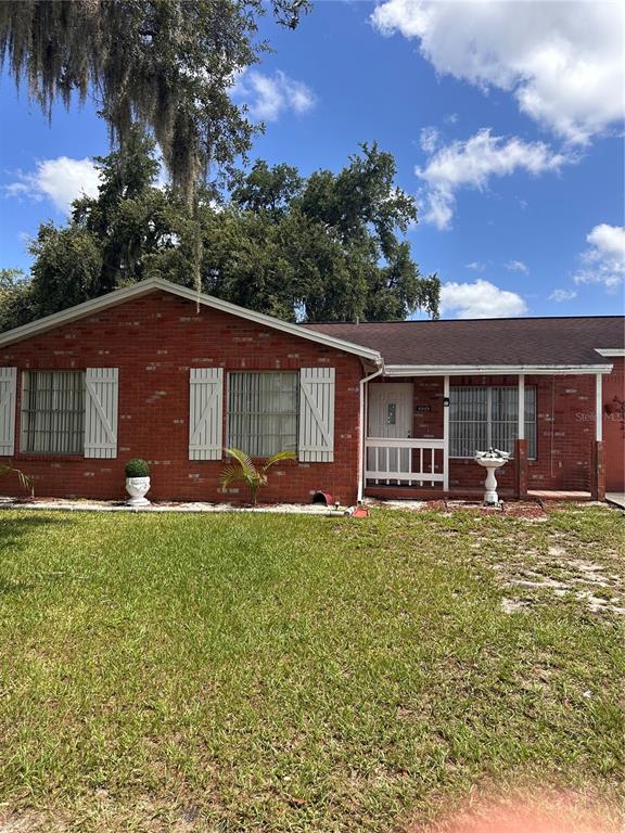A single-story red brick house features white shutters, a front porch, and a grassy lawn — 8848 OAK CIRCLE, TAMPA, FL