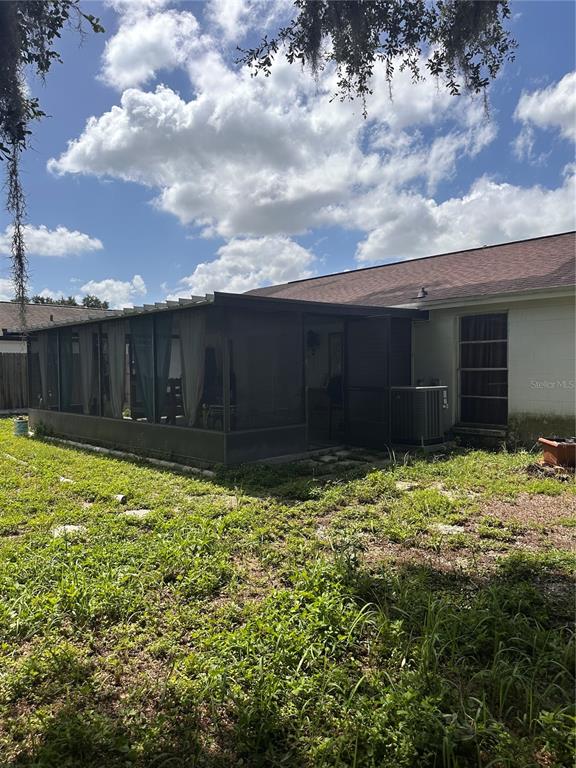 A backyard view of a house with a screened-in porch and an outdoor air conditioning unit — 8848 OAK CIRCLE, TAMPA, FL