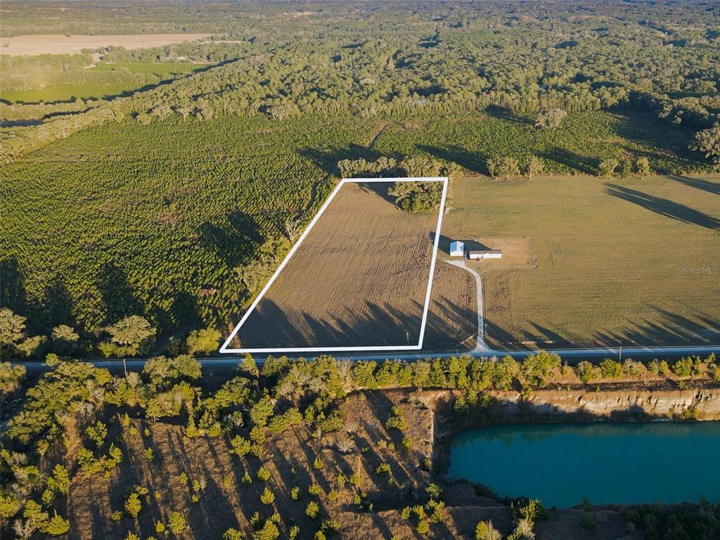 An aerial view shows a rectangular plot of land bordered by trees and a road — 001 NW 202ND STREET, NEWBERRY, FL
